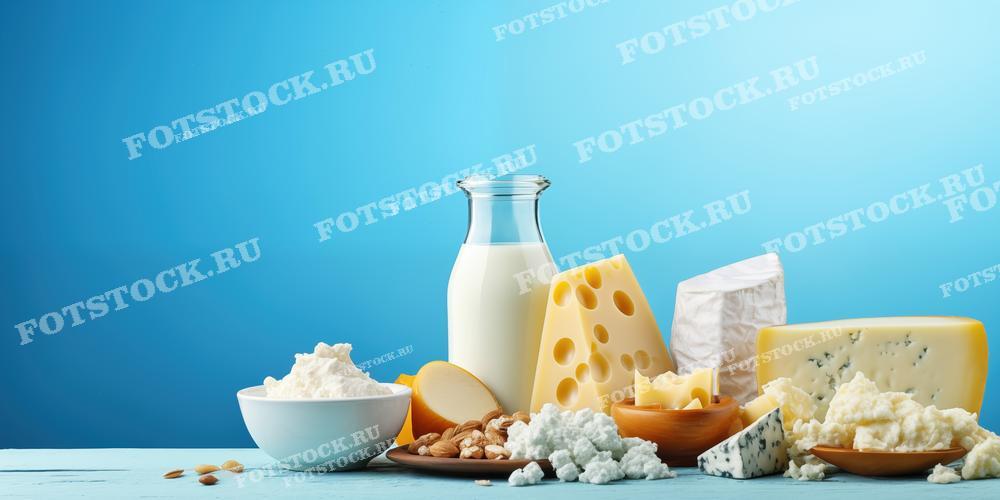 На фотографии изображены разнообразные молочные продукты, такие как молоко в бутылке, сыры разных видов и творог. Снимок демонстрирует натуральные и свежие молочные продукты, которые могут использоваться в домашней кухне.